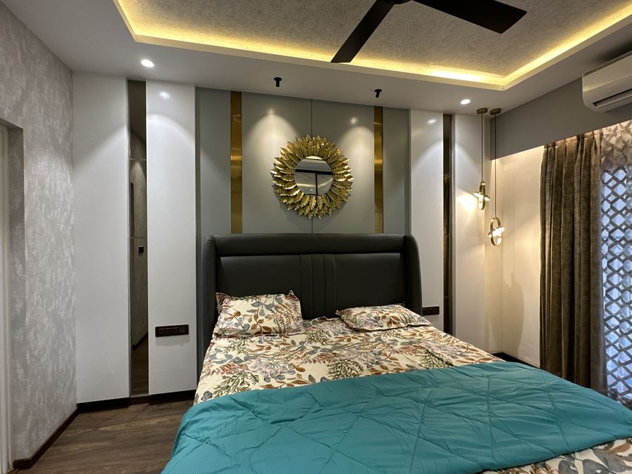 Bedroom with upholstered headboard and gold sunburst mirror feature wall